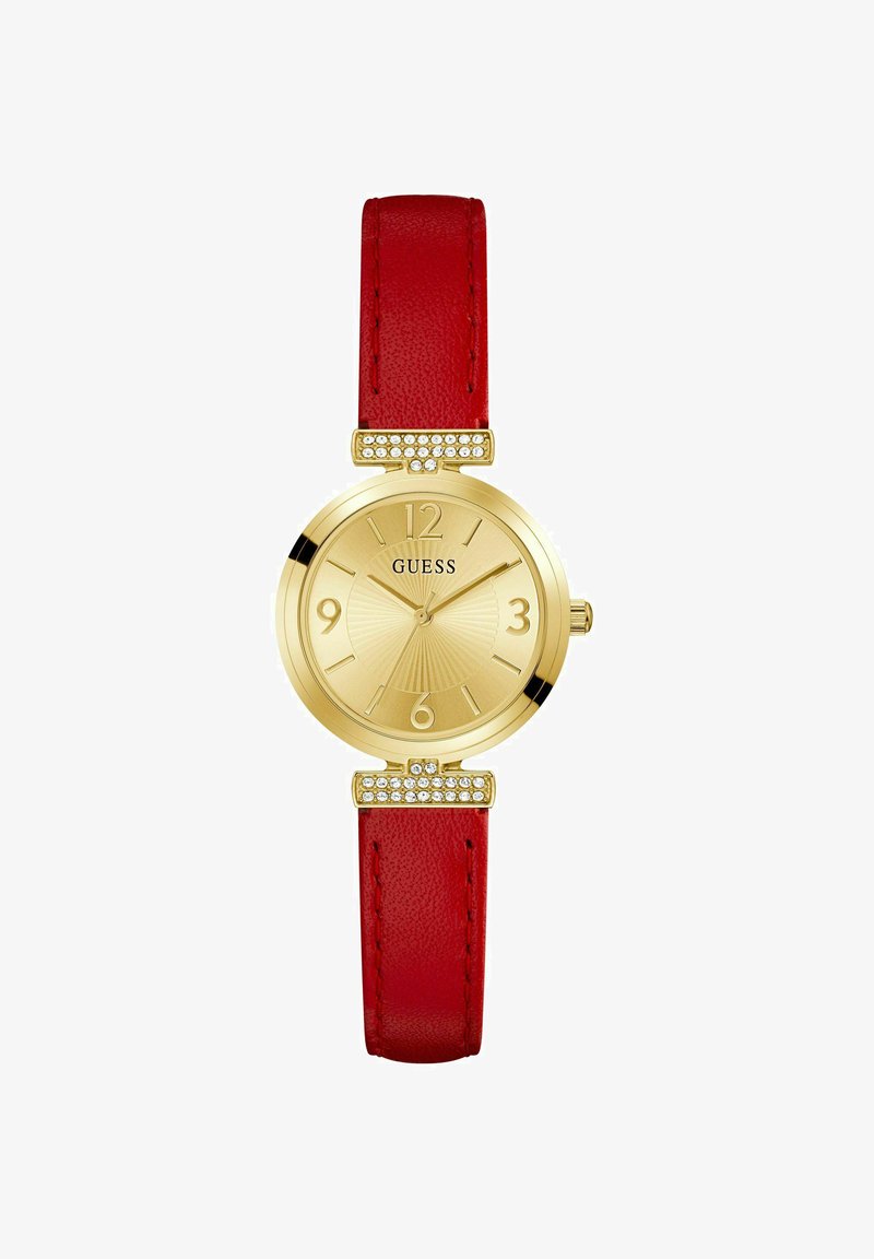 Reloj dorado con una esfera texturizada, correa de cuero rojo y herrajes con cristales en los soportes. Presenta marcadores de hora en negrita.
