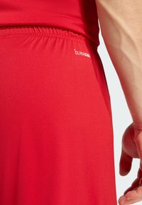 Κόκκινο αθλητικό πουκάμισο με λεία υφή και ελαστική μέση, με λευκό λογότυπο "CLIMACOOL" στο πλάι.