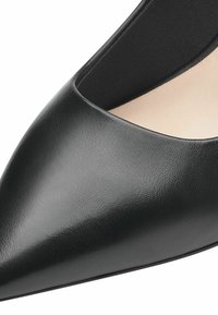 Sorte læder pumps med spids tå, der har en glat tekstur, minimalistisk design og en lavskåret silhuet på siderne for et strømlinet udseende.
