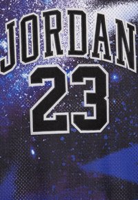 Czarny trykot z napisem "JORDAN" oraz numerem "23" w wyrazistym czarno-białym haftowaniu na tle teksturowanego wzoru galaktyki w odcieniach fioletu i czerni.