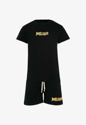 Set composto da T-shirt nera a maniche corte e pantaloncini con la scritta gialla "Just Cavalli Little Rogue" sul petto e sulla gamba sinistra, con coulisse bianca sui pantaloncini.