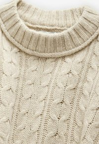 Geflochtene Strickjacke in Cremefarbe mit einem gerippten Kragen und strukturierten Mustern. Weiches, grobes Wollmaterial mit sichtbaren Nähten.