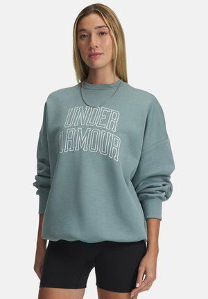 Light teal sweatshirt with "UNDER ARMOUR" printed in white, featuring a crew neck and dropped shoulder seams, paired with black shorts.