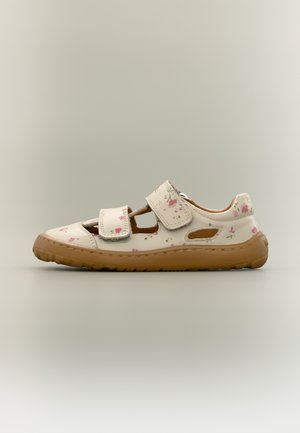 Άσπρο δερμάτινο σανδάλι με ανθικό σχέδιο, διαθέτει δύο λουράκια με βέλκρο και ανοιχτό καφέ καουτσούκ σόλα. Ανοίγματα στα πλάγια για καλύτερη αναπνοή.