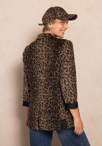 Leoprint-Blazer aus weichem Stoff mit schwarzen Akzenten an den Bündchen, mit weitem Schnitt, Reverskragen und einem Etikett am Saum.