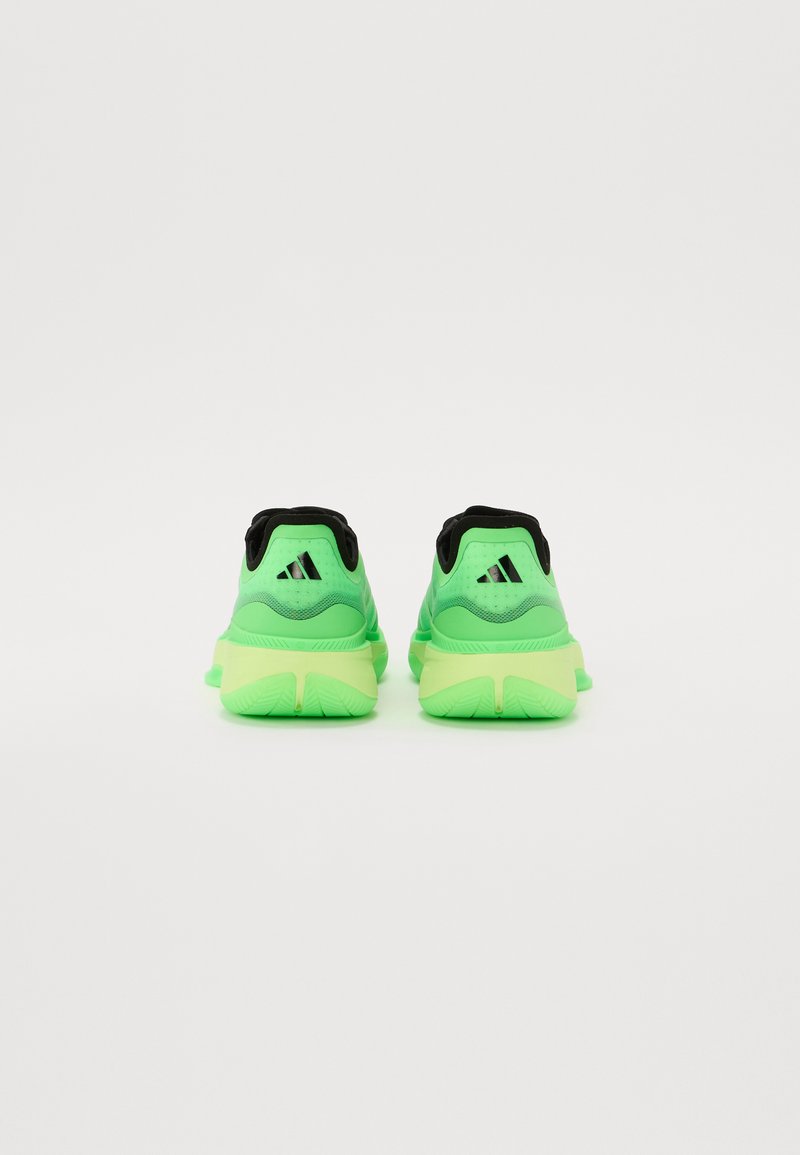 Zapatillas deportivas verdes con un collar negro, que cuentan con una parte superior de malla texturizada y suela de goma contrastante. Logotipo de tres rayas destacado en el talón.