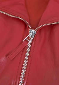 Rote Lederjacke mit silbernem Reißverschluss, ausgestattet mit einer glatten Textur und einem Stehkragen, der Stecknähte entlang der Nähte zeigt.