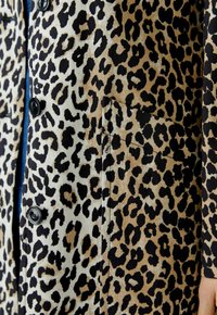 Leopardenmuster-Blazer in Beige und Schwarz, mit glatter Textur, vier Knöpfen und einer versteckten Seitentasche.