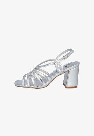 Sándalo de tacón alto metálico plateado con punta abierta, diseño de múltiples tiras, tirante en el tobillo y tacón bloque. Textura suave con un acabado brillante.