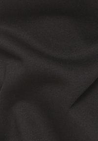 Schwarzer Stoff mit einer glatten, weichen Textur, die feine Rippungen und einen subtilen Glanz zeigt, drapiert, um seine Form und Konturen zu betonen.