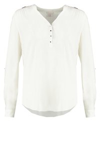 Blouse blanche à manches longues en tissu léger, avec un col en V, une patte de boutonnage à cinq boutons et un détail de manche froncée. Texture lisse, coupe d écontractée.