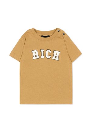 Beżowa koszulka z krótkim rękawem dla malucha z białymi literami blokowymi tworzącymi napis "RICH" na piersi oraz małymi czarnymi guzikami na lewym ramieniu.