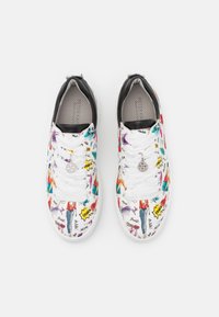 Zapatilla blanca con estampados de moda coloridos, acentos negros y un charm plateado. Presenta un upper de textil, puntera redonda y diseño de cordones.