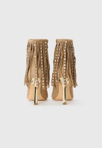 Tansuede hoge hakken enkellaarzen met gouden stilettohakken, versierd met franjes en kristallen studs aan de achterkant en zijkanten.