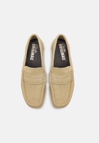 Beige semsket loafers med rund tå, med sydde detaljer og myk tekstur. Svart innersåle med "Clarks Originals" merke.