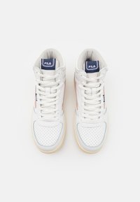 Vita höga sneakers i vitt med en perforerad läderöverdel, ljusrosa detaljer och en krämfärgad gummisula. "Fila"-logotyp på tungan och sidan.
