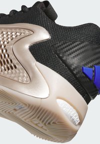 Černá sportovní bota s texturovaným svrškem, metalickými zlatými akcenty, detaily z uhlíkových vláken a gumovou podrážkou s vzorem pro dobrý grip.