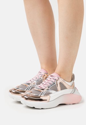 Silberne und rosa Sneaker mit Netz-Obermaterial, metallischen Akzenten, runden Zehen und dicken weißen Sohlen. Die Schnürsenkel sind rosa mit dem Logo der Marke an der Seite.