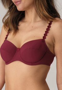 Sostén burdeos con aros, copas acolchadas y tirantes decorativos con volantes. Tejido suave con un detalle de botón en el centro.