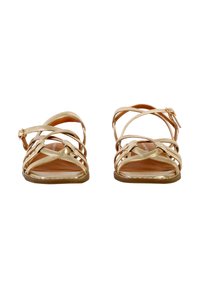 Sandali metallici dorati con cinturini incrociati, design aperto sulla punta e fibbia alla caviglia. Suola piatta con sottopiede texturizzato color tan.