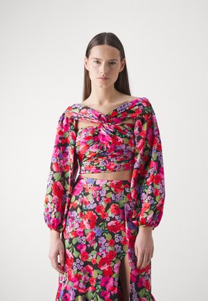 Costum floral format din două piese, cu un top off-shoulder legat, cu mâneci bufante și o fustă cu fante înaltă, realizat dintr-un material vibrant și ușor.