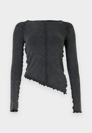 Haut gris foncé à manches longues avec ourlet asymétrique, coutures ondulées cousues verticalement et autour des bords, fabriqué en tissu texturé.