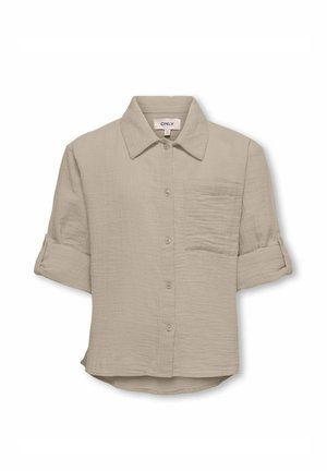 Chemise beige à manches longues retroussées, boutonnée sur le devant, avec une poche poitrine unique et un col classique.