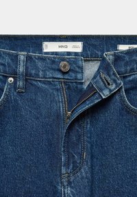 Jeans de mezclilla de color azul oscuro con cierre de cremallera, botón plateado y diseño estándar de cinco bolsillos. Presenta costuras visibles y una etiqueta de la marca.