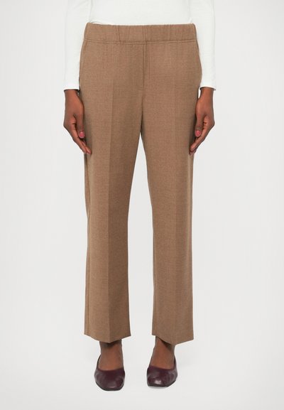 Pantalons marron à jambes droites avec une taille élastique, fabriqués en tissu texturé. Portés avec des chaussures bordeaux foncé.
