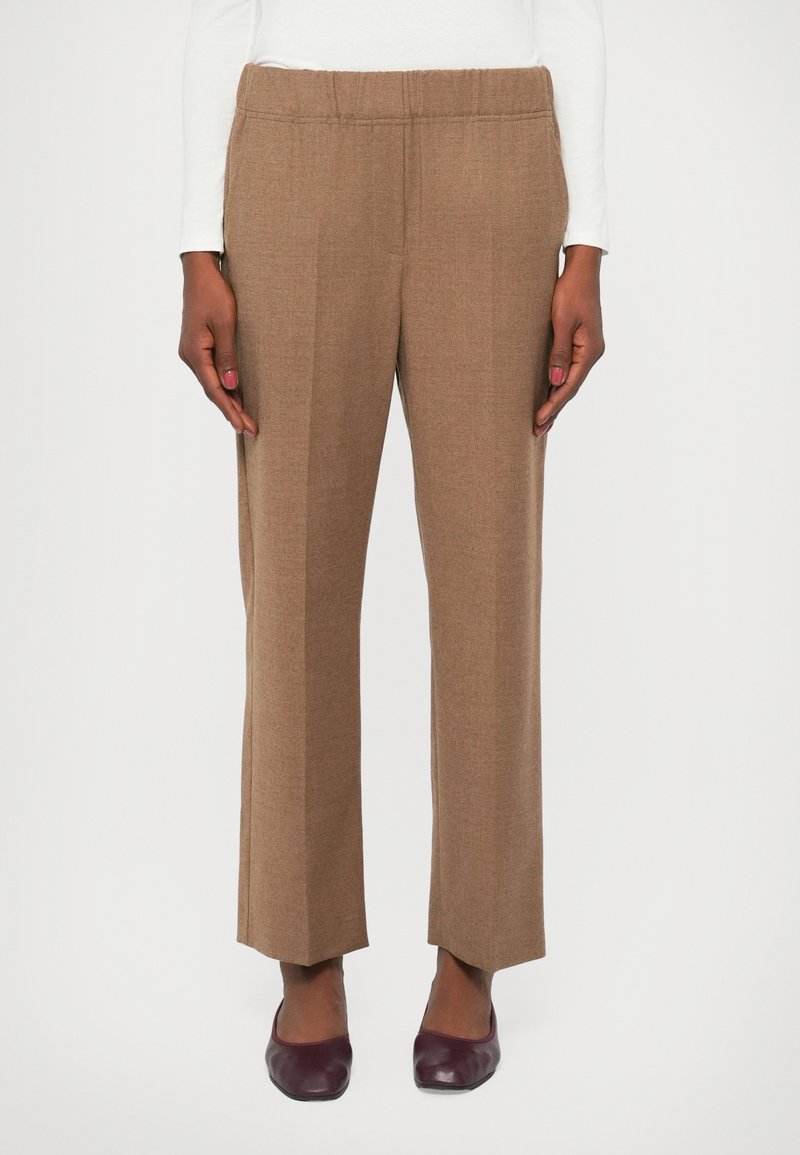 Pantaloni maro cu picioare drepte, cu un waistband elastic, dintr-un material texturat. Purtați cu pantofi de culoare burgundă închisă.