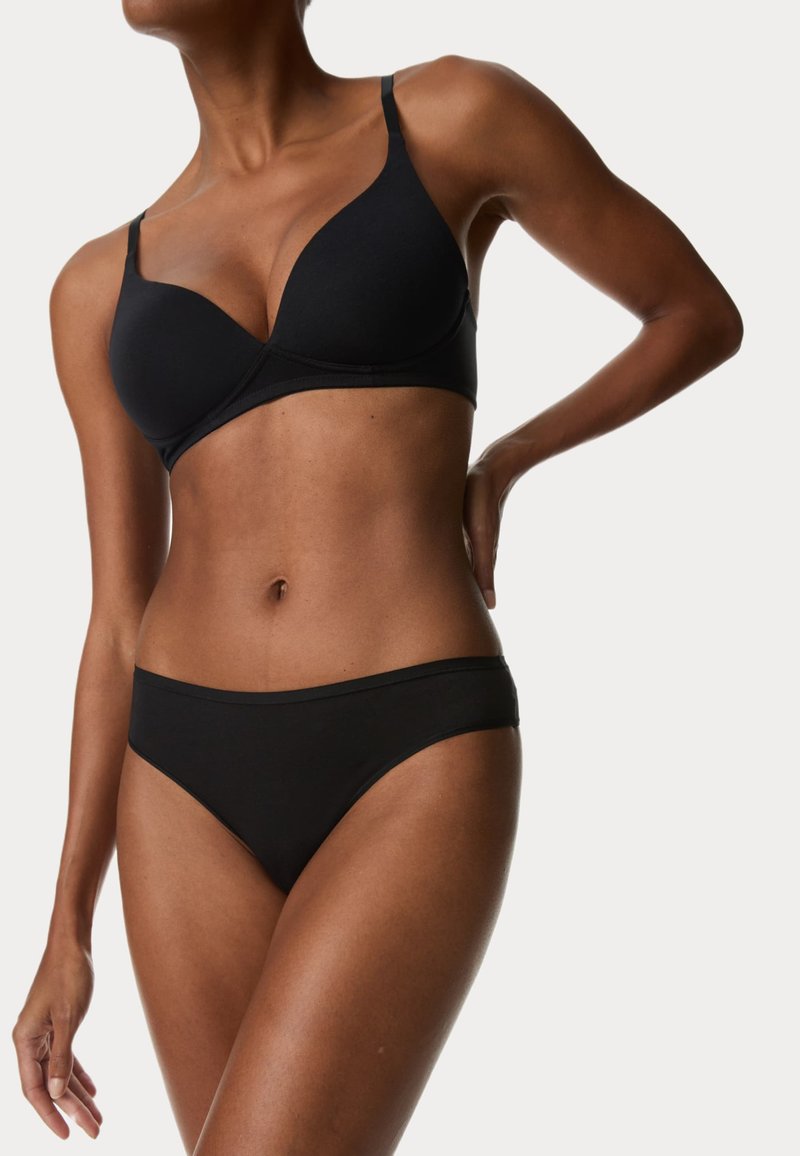 Reggiseno nero con scollatura profonda e spalline regolabili, abbinato a slip a vita bassa coordinati. Texture liscia e costruzione senza cuciture.