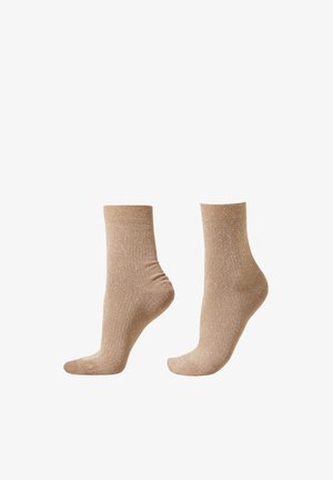 Chaussettes beige en tissu doux avec une texture côtelée et de subtils éclats métalliques. Longueur cheville avec un poignet confortable pour un maintien sécurisé.