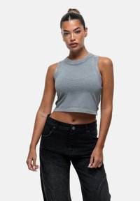 Grijze korte tanktop van gladde stof, met een ronde halslijn en mouwloos ontwerp, gecombineerd met hoogsluitende zwarte broek.