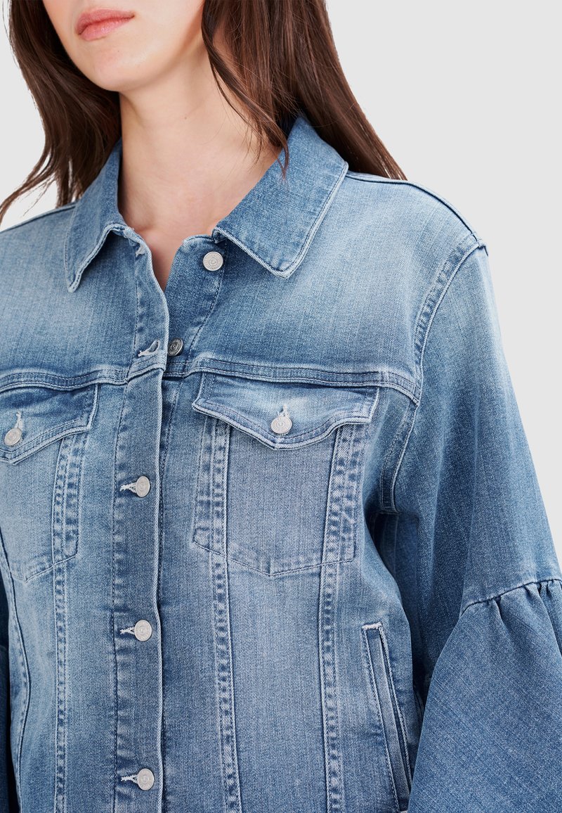 Hellblaues Jeansjackett mit klassischem Kragen, vorderem Knopfverschluss und zwei Brusttaschen. Hat lockere, trompetenförmige Ärmel.