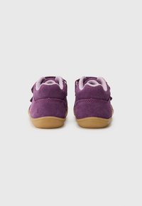 Sapatos infantis de camurça roxos com um forro rosa suave, apresentando tiras ajustáveis e uma sola de borracha texturizada para aderência.