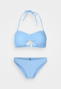 Conjunto de bikini azul claro com um top bandeau com detalhe de nó central e alças tipo halter, combinado com um bottom hipster correspondente.
