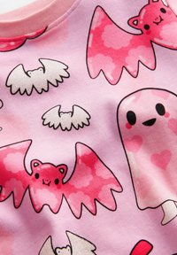 Rosa T-Shirt mit verspielten Mustern von Cartoon-Fledermäusen und einem Geist, in verschiedenen Rosatönen, weißen Akzenten und Herzen-Motiven.