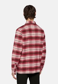 Rood en wit geruite flanellen shirt met een kraag, lange mouwen en knoopmanchetten. Voorzien van een geblokt patroon en een zachte textuur.