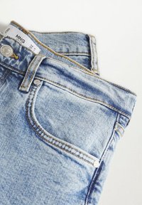 Light blue denim jeans with a slightly faded texture, featuring contrasting yellow stitching, a front pocket, and a metal button closure.