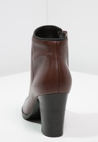 Ruskean nahkanilkkureissa on sileä pinta, pyöreä kärki, teksturoitu musta korko ja vetoketju takana.