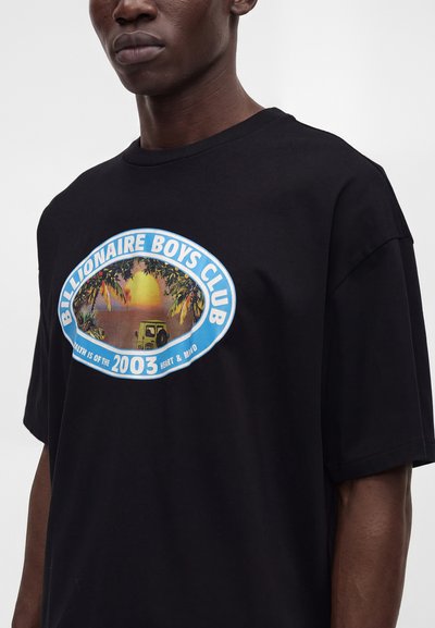 Black t-shirt with blue oval logo reading "Billionaire Boys Club" and a sunset and jeep graphic on the front, worn by a person.