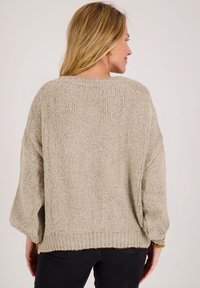 Beige gebreide trui met een ontspannen pasvorm, verlaagde schouders, geribbelde manchetten en zoom. Gestructureerde stof zorgt voor een gezellige uitstraling.