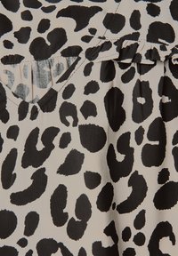 Tessuto a stampa leopardata con colori nero e beige, caratterizzato da un dettaglio a pieghe testurizzate nel colletto. Texture morbida e liscia in generale.