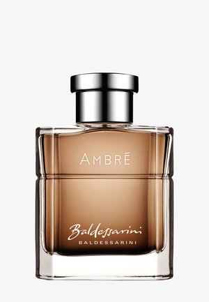 Flacon de parfum en verre transparent avec liquide ambré, bouchon argenté, étiqueté "AMBRÉ Baldessarini" sur le devant.