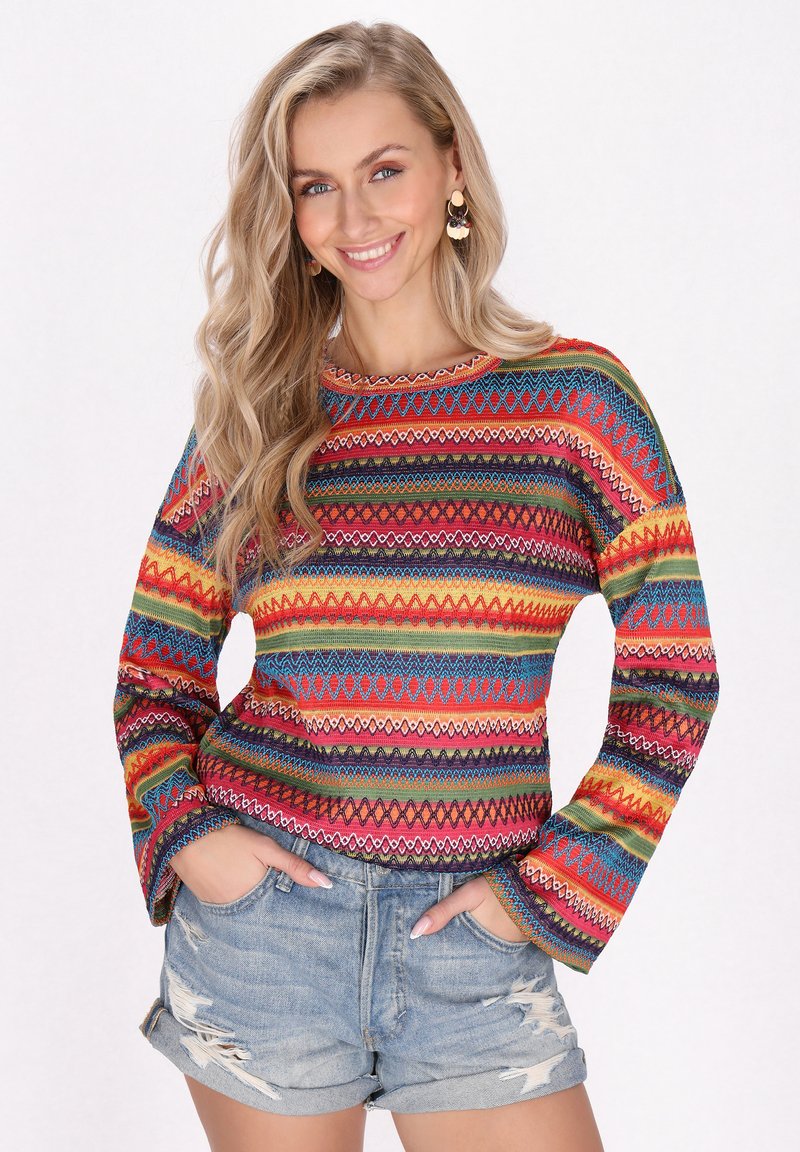 Maglietta a maniche lunghe colorata con un mix di motivi rossi, blu, gialli e verdi. Presenta un colletto tondo e un tessuto testurizzato. Abbinata a pantaloni shorts in denim.