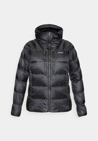 Zwarte geïsoleerde pufferjack met capuchon, rits aan de voorkant, twee verticale borstzakken met ritsen en zijzakken met ritsen, Patagonia-logo zichtbaar.