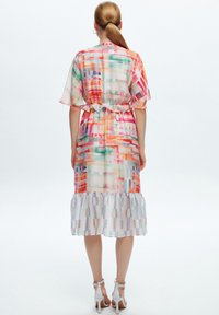 Robe multicolore à coupe décontractée, avec une taille froncée, des manches courtes et un ourlet à volants, fabriquée dans un tissu léger et transparent.