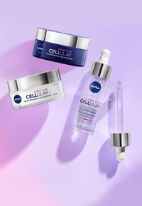 Three Nivea skin care products: a dark blue jar, a white jar with silver lid, and a clear serum bottle with a dropper, set against a gradient purple background.