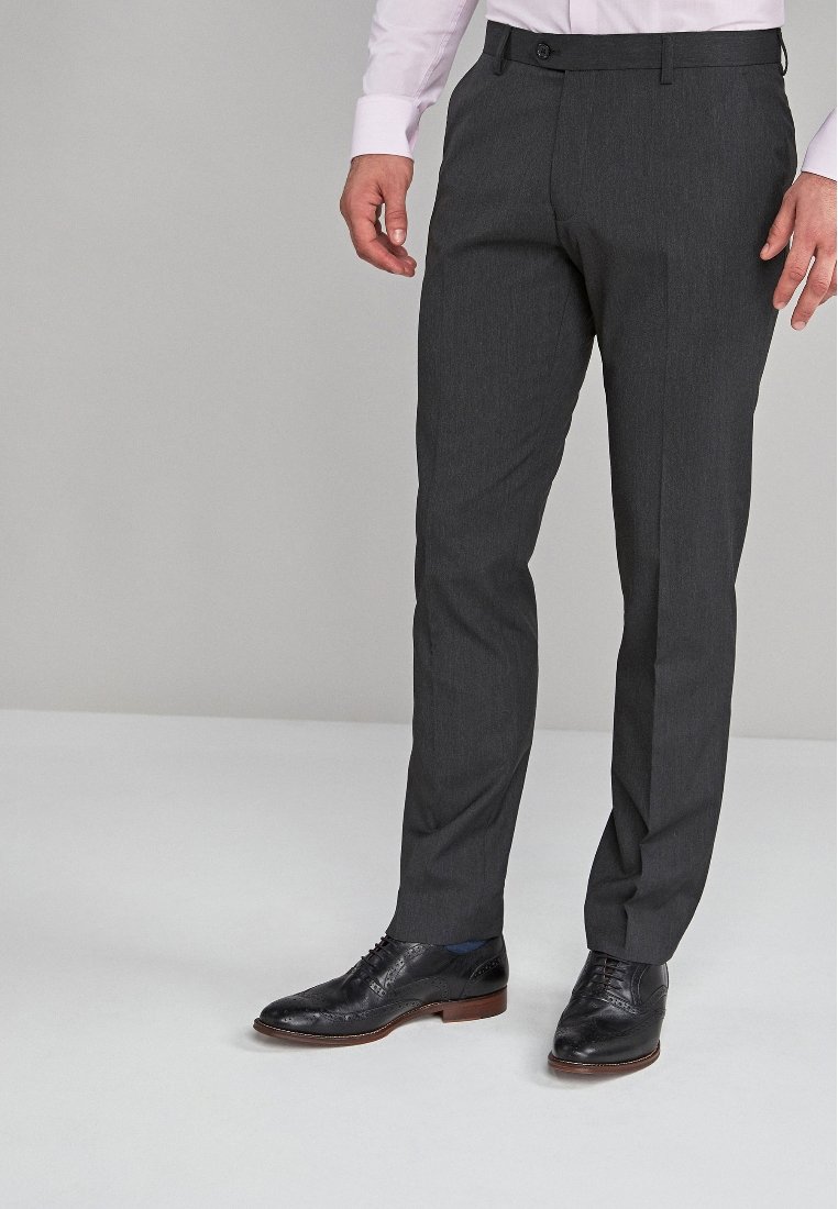 Pantalons gris sur mesure avec une texture lisse, présentant une taille plate et des passants de ceinture, assortis à des chaussures de ville noires.