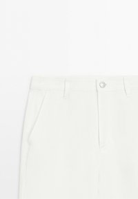 White pants waistband with belt loops, a silver button closure, and side pockets on a plain background.